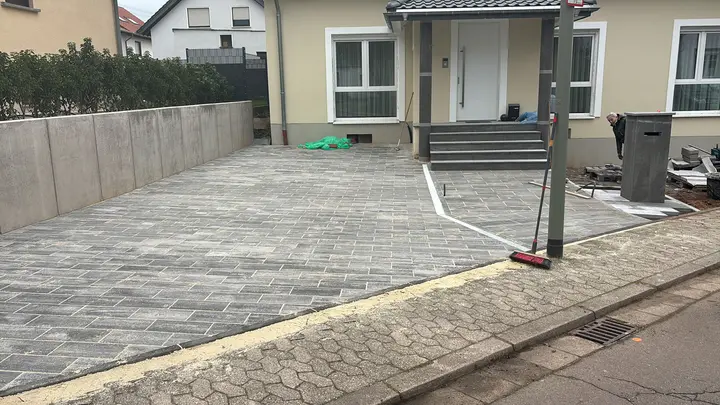 Fertige Einfahrt in grauen Platten vor dem sanierten Haus