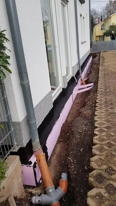 Geöffneter Graben an der Hauswand mit Dämmung