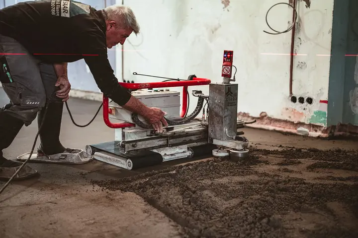 Mitarbeiter richtet den Estrichroboter aus